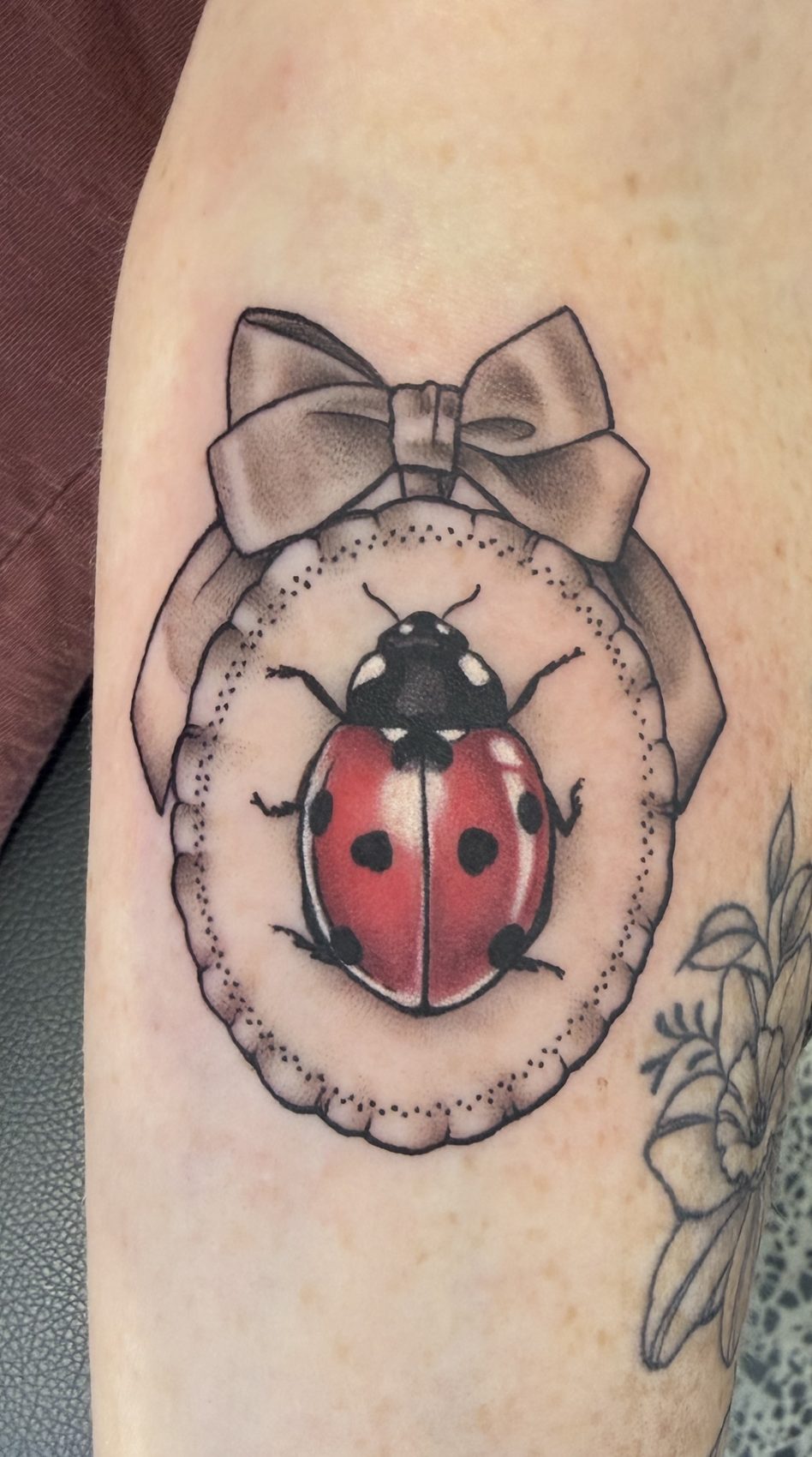 Neo-traditional ladybird and bow tattoo